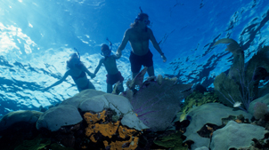 Man and two young children snorkeling underwater